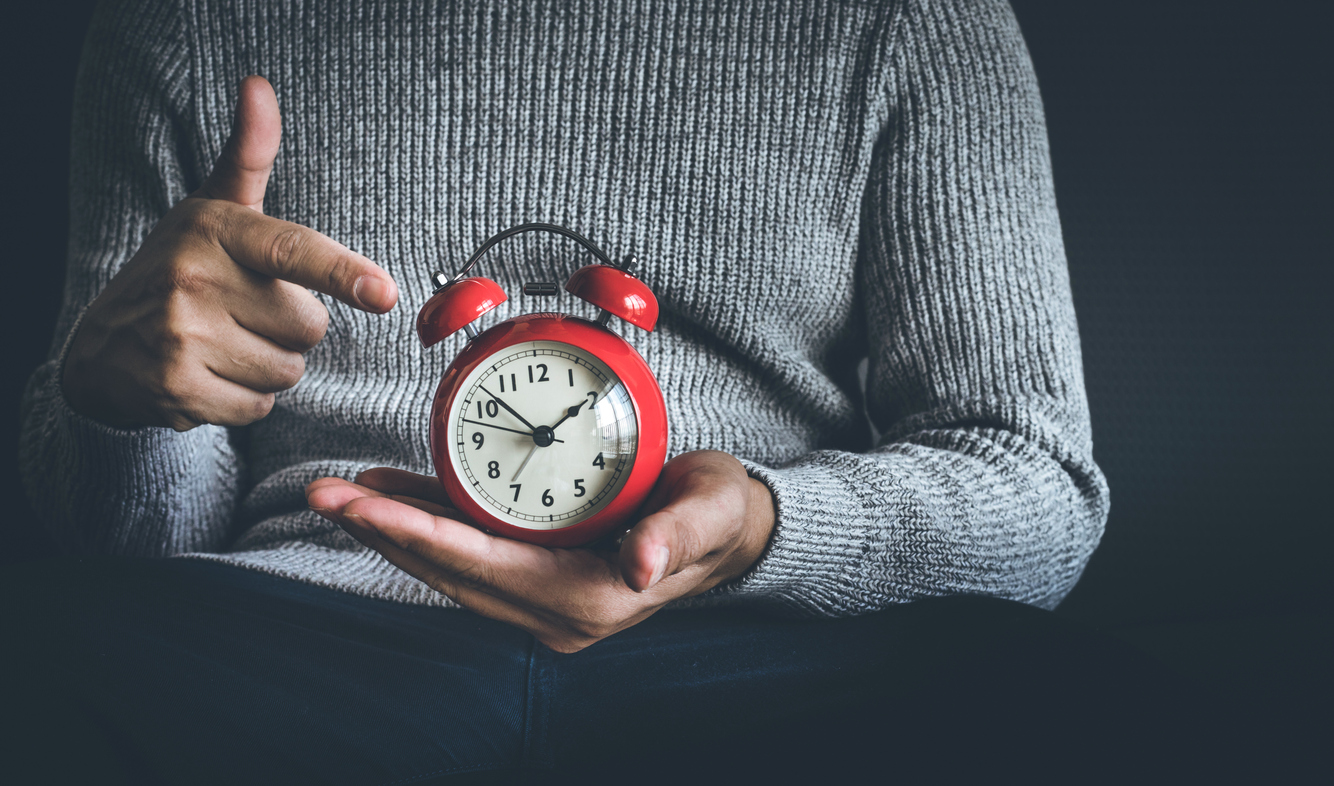 Time and life concepts with young man holding alarm clock and sitting on sofa.Motivation images ideas