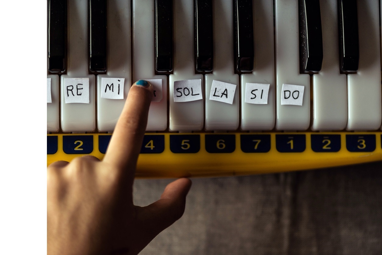 Young girl learning to play piano. To learn faster she attached the names of the notes to the piano keys